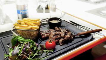 Uma refeição com bife, batatas fritas e salada em um prato preto.