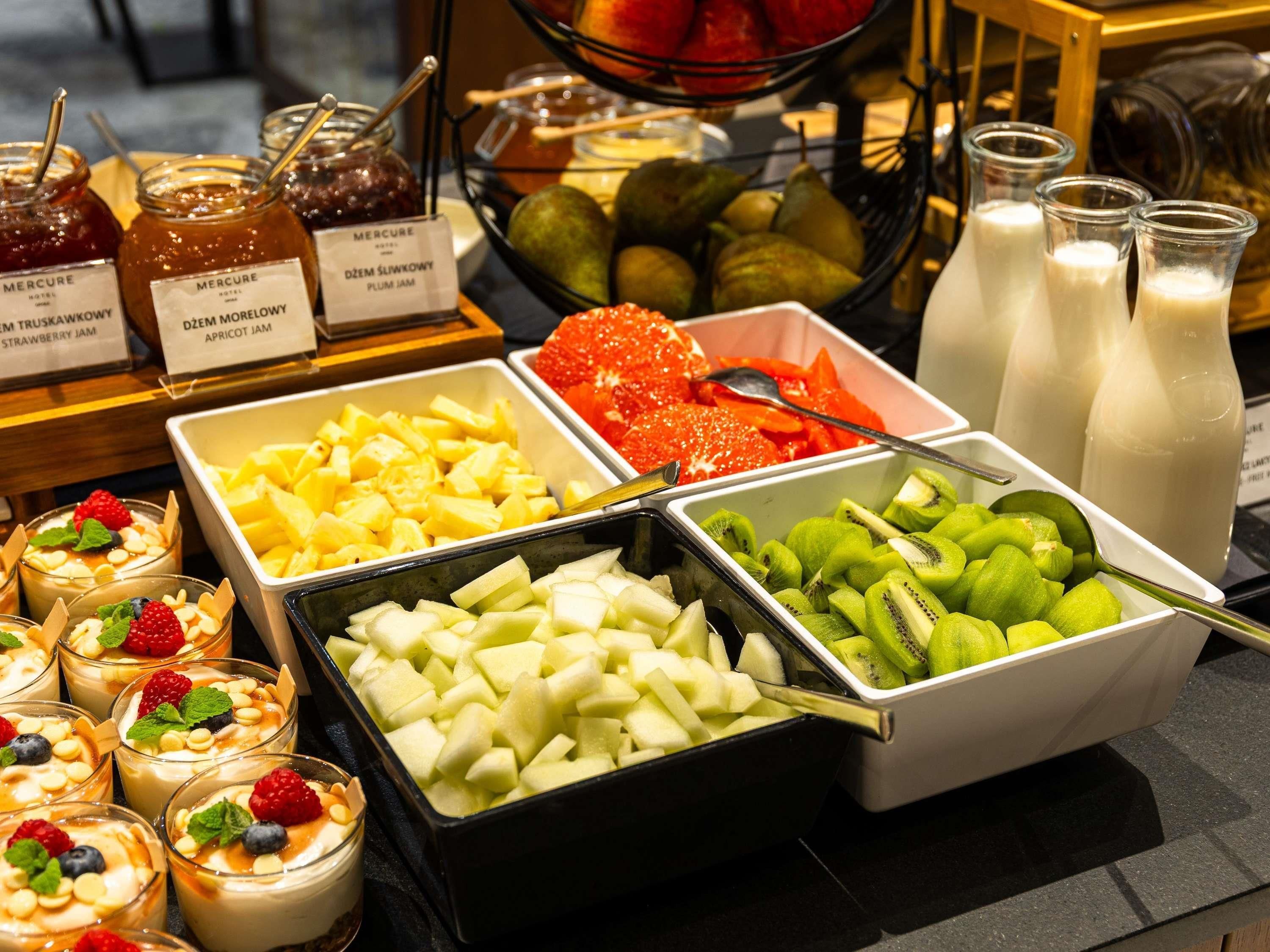 A buffet with various food items including fruit, yogurt, and jams.