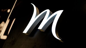 Una letra 'M' grande e iluminada sobre un fondo oscuro.