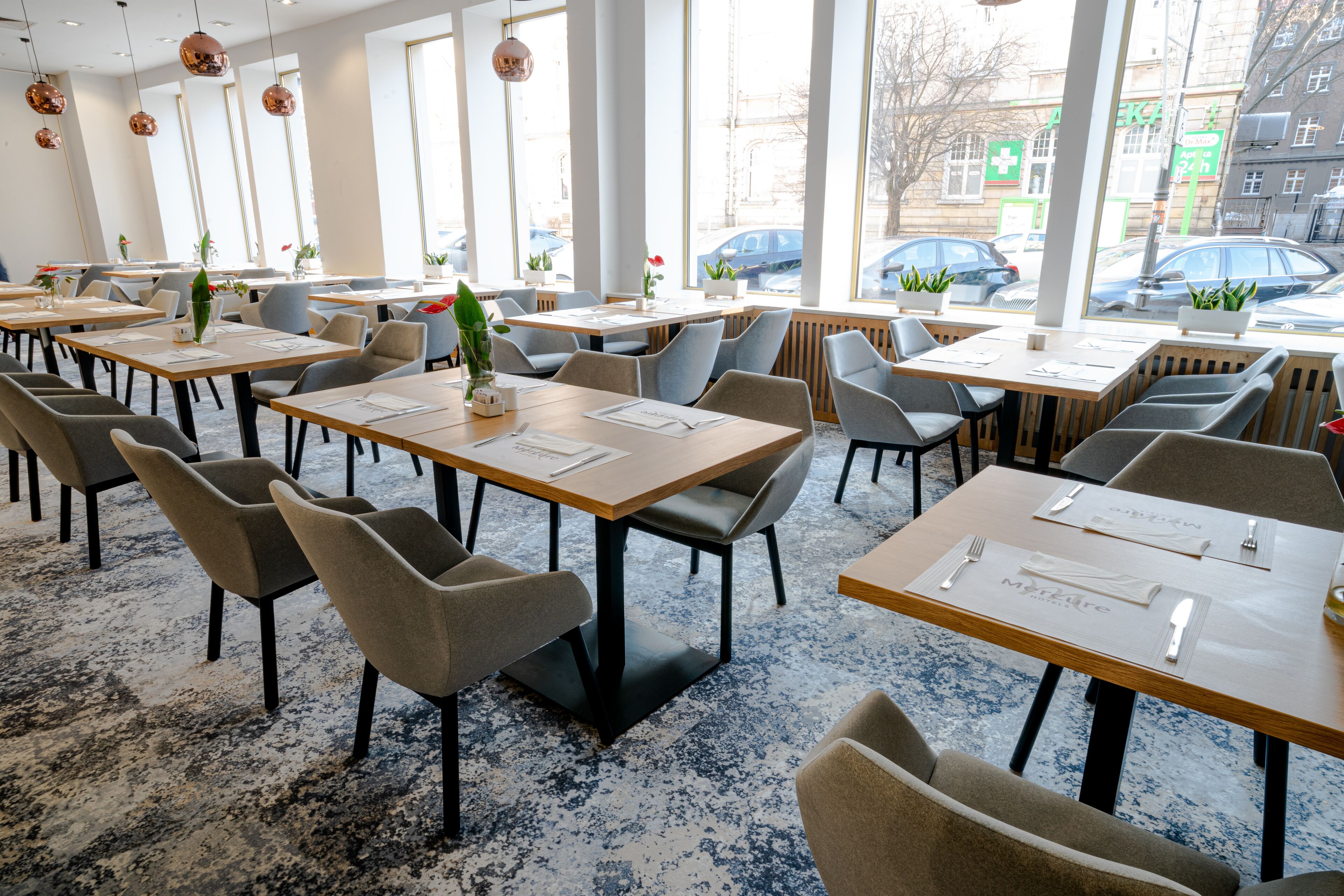 Un vaste espace dédié à la salle à manger, avec de nombreuses tables et chaises, de grandes fenêtres et une vue sur la rue.