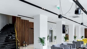 A modern lobby with a staircase, seating area, and a reception desk.