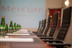 A conference room with a long table, chairs, and rows of green bottles.