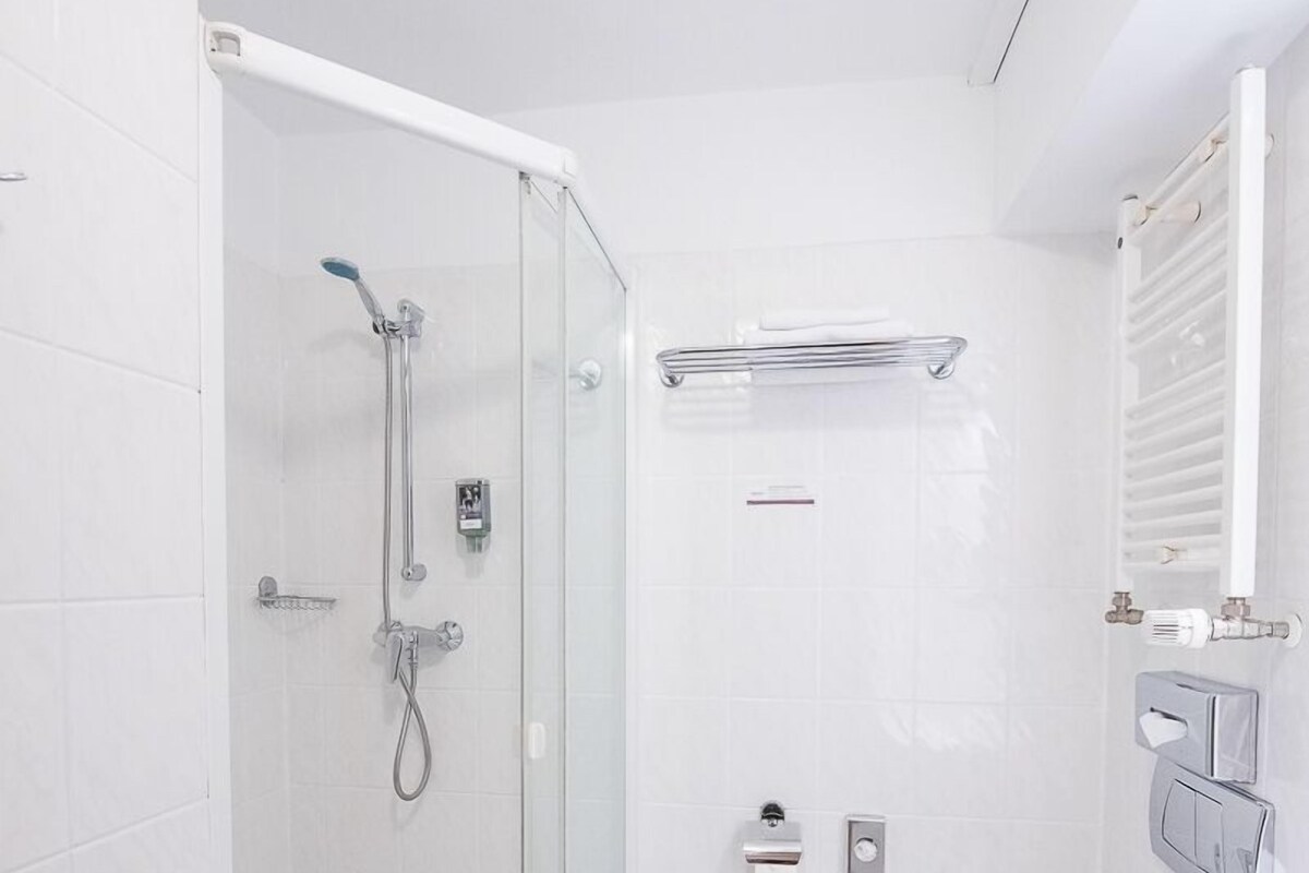 A modern bathroom with a glass-enclosed shower, a white toilet, and a white sink.