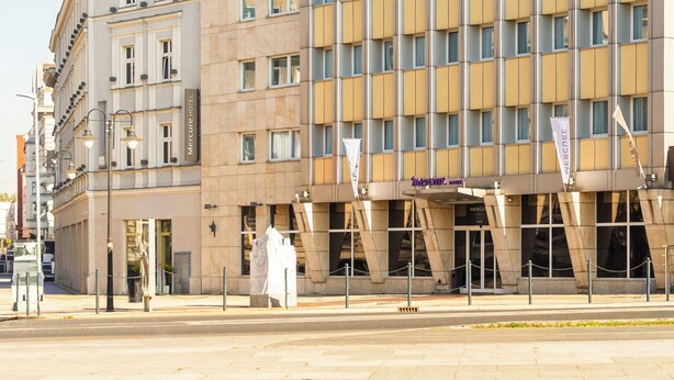 Un moderno edificio de hotel con una fachada de ventanas en forma de cuadrícula y un letrero que dice "Monaco Hotel".