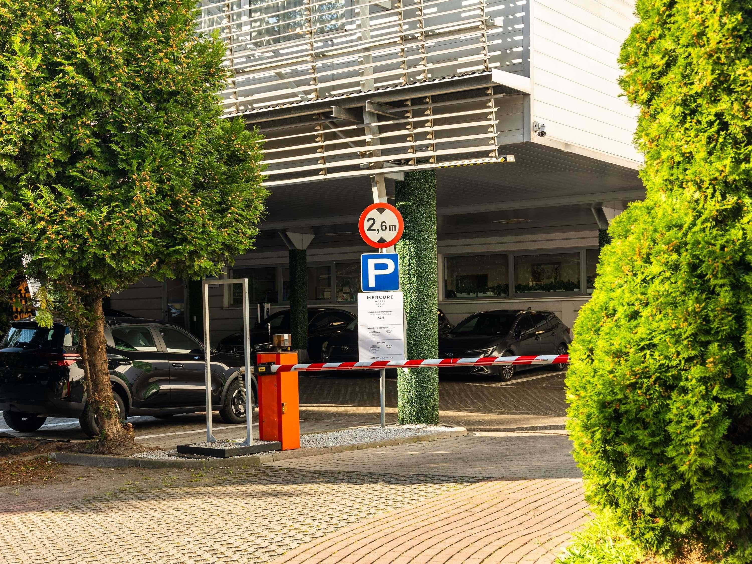 A hotel entrance with a 2.6m height restriction sign, a parking sign, and a gated entrance.