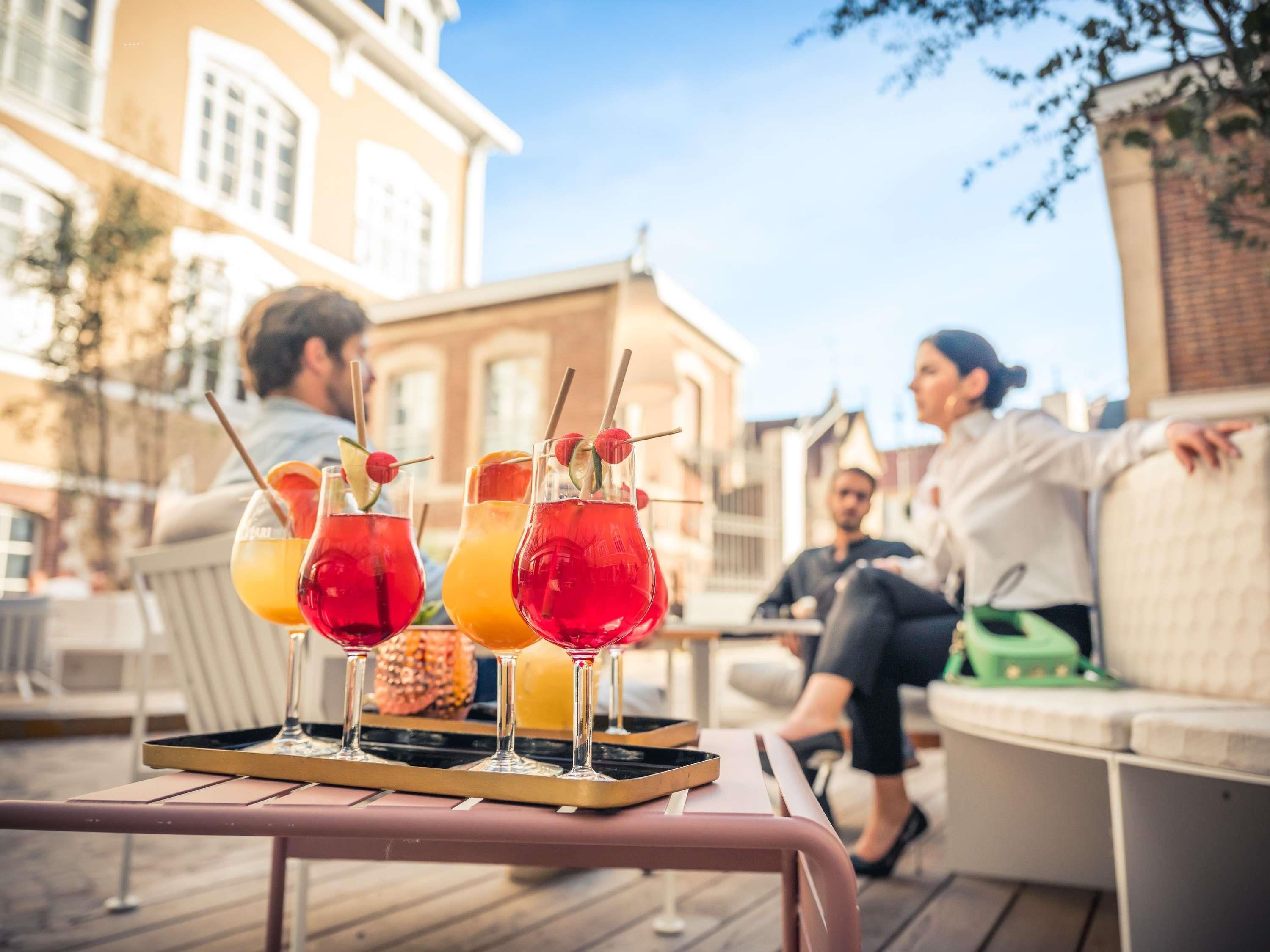 Eine Terrassenfläche mit Sitzgelegenheiten und einem Tisch mit Getränken.