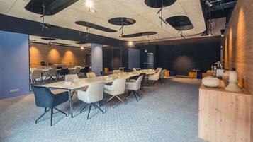 A conference room with tables and chairs, a wooden accent wall, and a patterned carpet.