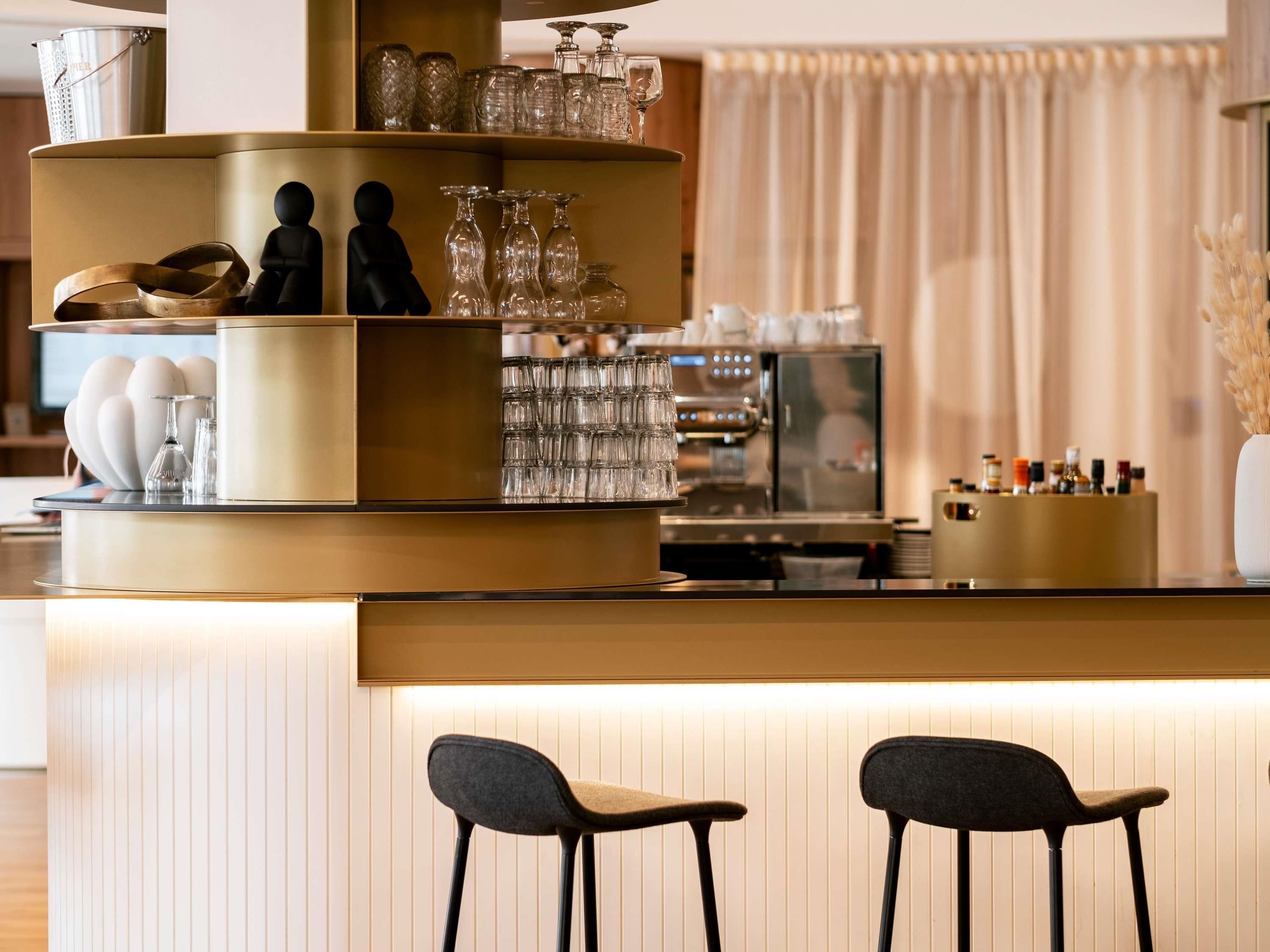 A bar area with a counter, stools, and various glassware.