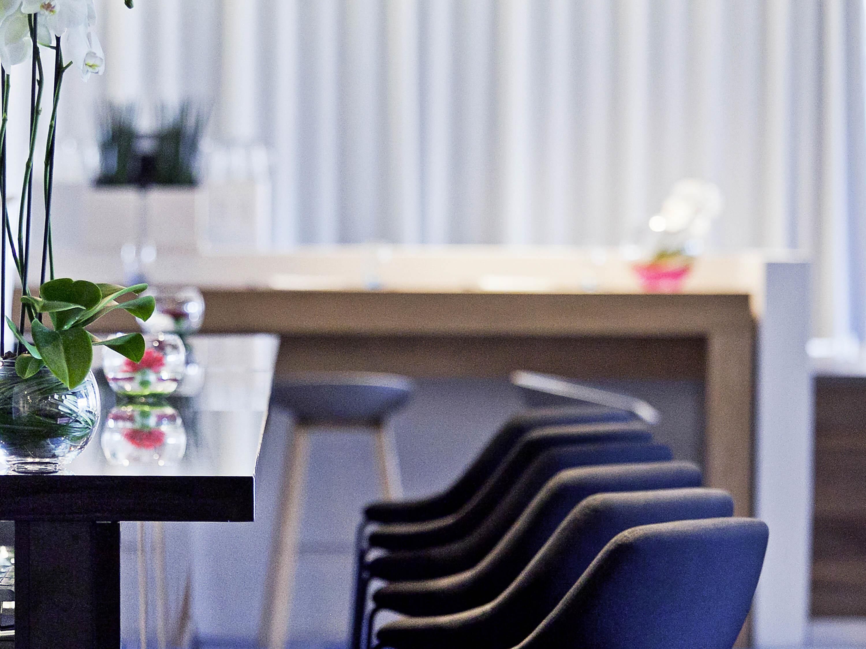 Ein Hotelzimmer mit Esstisch, Stühlen und einer Vase mit Blumen.