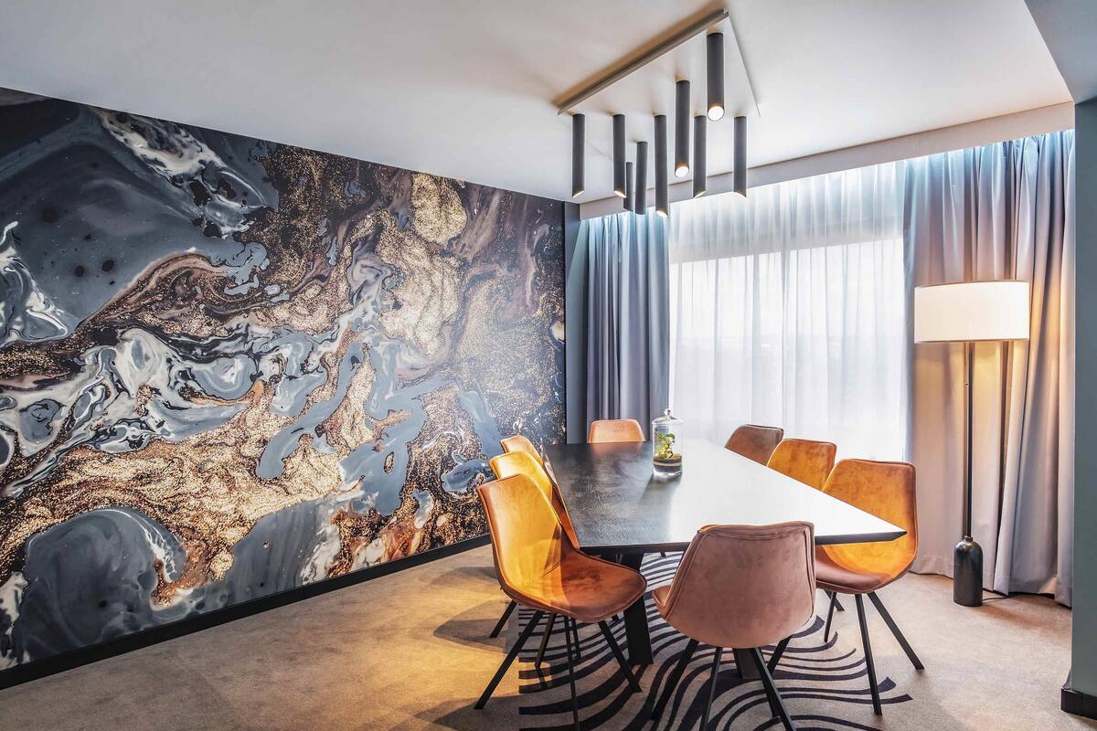 A modern conference room with a marble wall, a long table, and orange chairs.