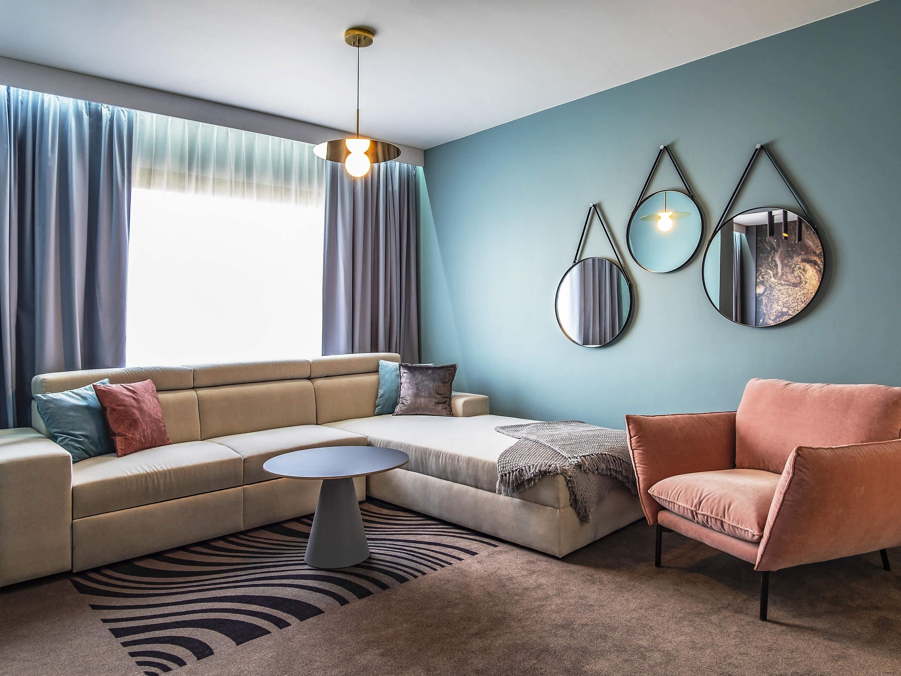 A modern living room with a sofa, armchair, coffee table, and wall-mounted mirrors.