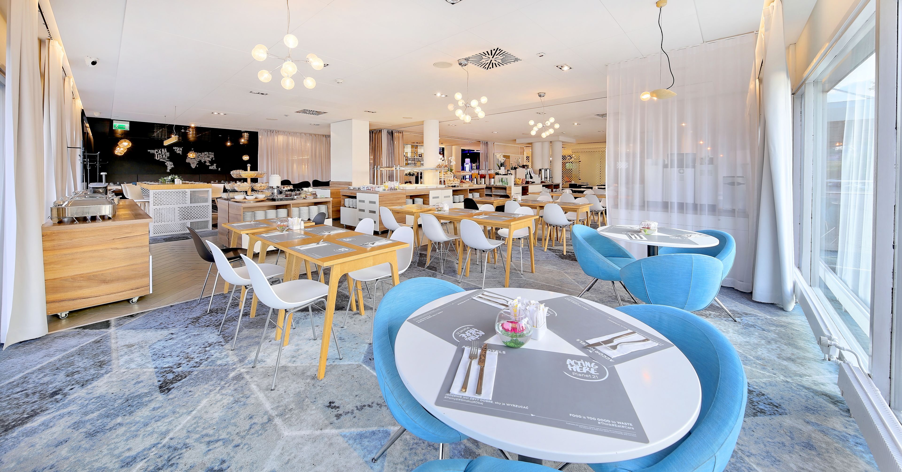 A modern restaurant with round tables and blue chairs, a bar area, and a view of the city through large windows.