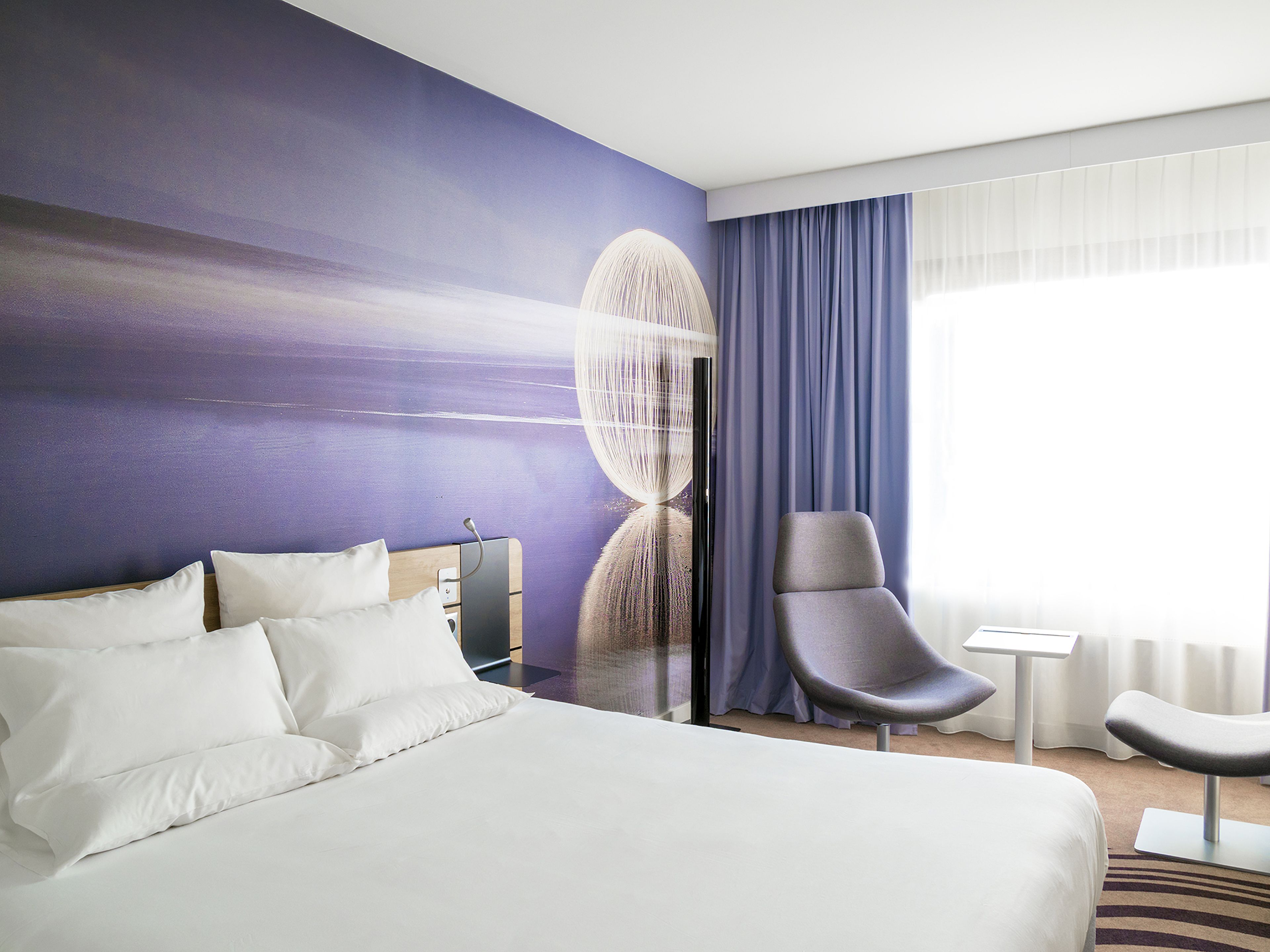 Une chambre d’hôtel moderne dotée d’un grand lit, d’un coin salon et offrant une vue sur l’extérieur.