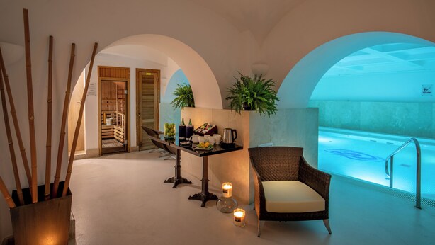 Zona de spa con piscina, área de descanso con una silla, mesa con detalles y decoración de bambú.