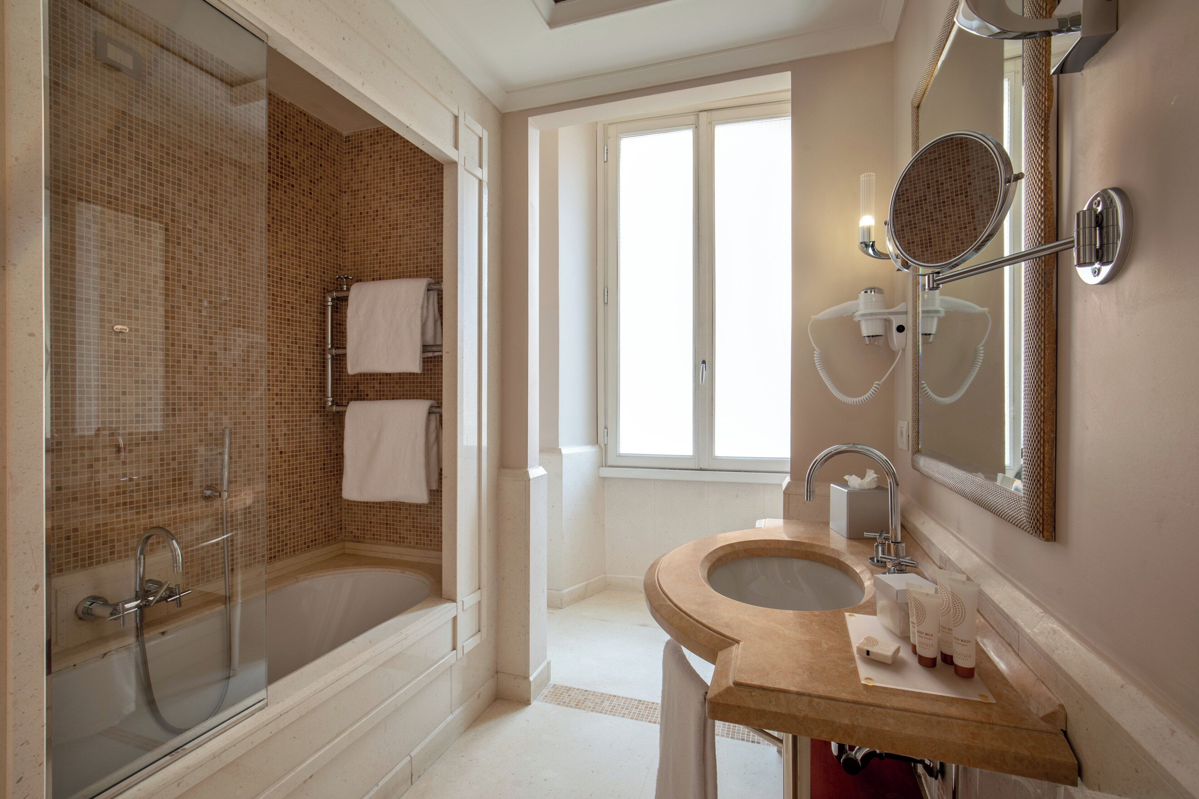 Un baño moderno con ducha de vidrio, una bañera independiente y un tocador con lavamanos y espejo.