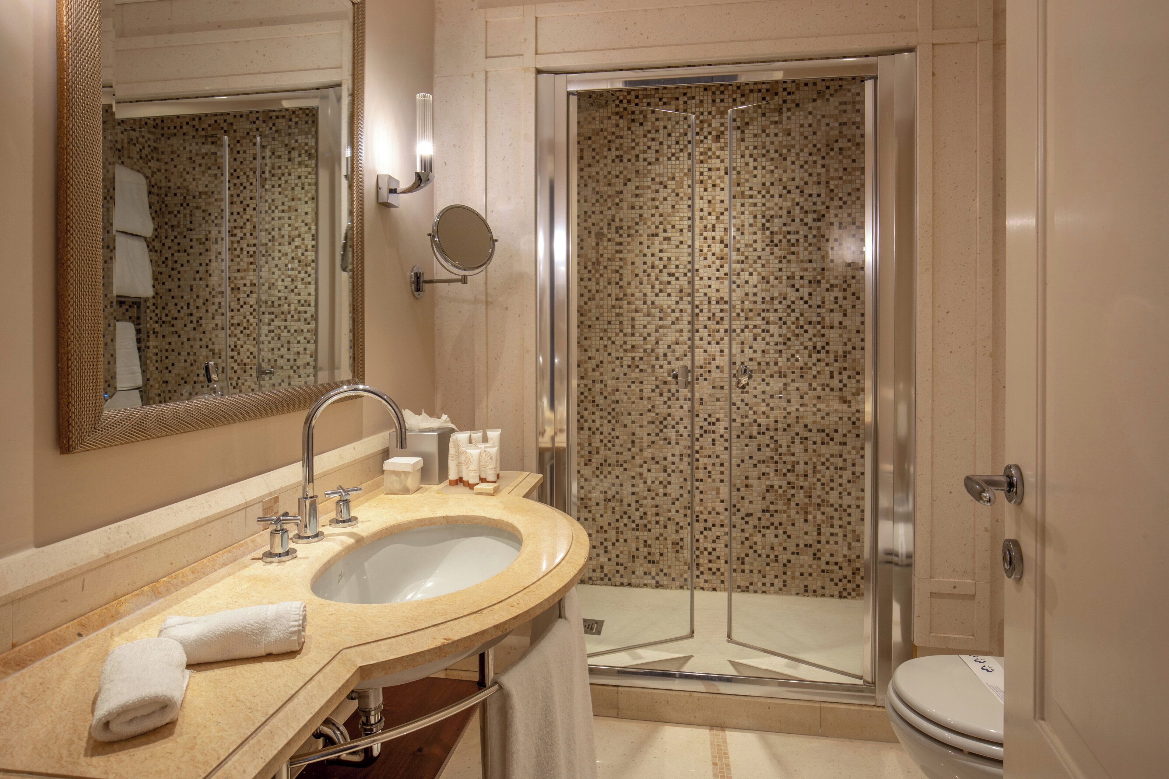 Een badkamer met een wastafel, spiegel en douche.