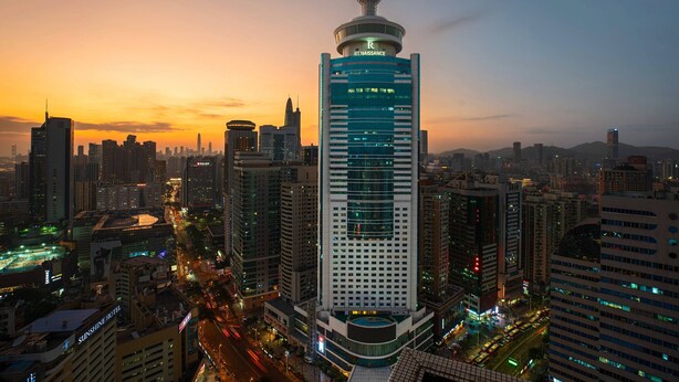 Un edificio de gran altura con una torre de observación esférica distintiva, rodeado de otros edificios altos en un paisaje urbano.