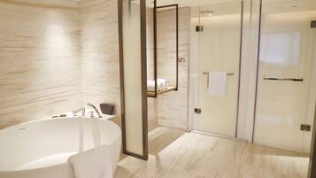 Un baño moderno con una bañera independiente, una ducha con mampara de vidrio y suelo de mármol.
