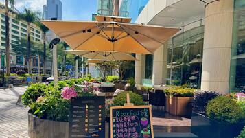 Un espace extérieur aménagé avec des parasols, un panneau affichant le menu et des plantes en pot.