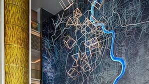 Un moderno vestíbulo con un mostrador de recepción de mármol, arte mural geométrico y una zona de estar central.
