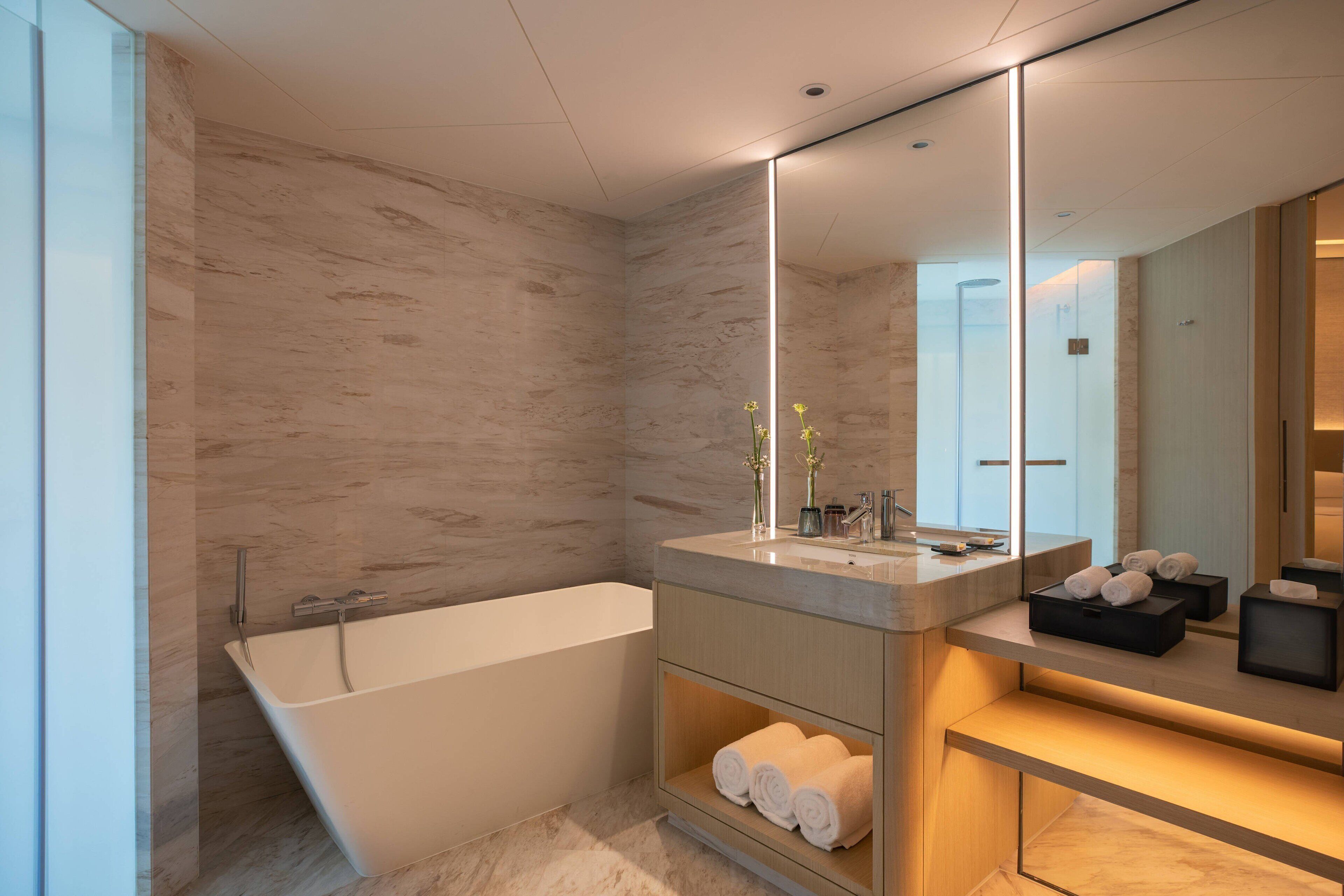 Une salle de bain moderne avec une baignoire sur pieds, un meuble-lavabo avec un miroir et des serviettes soigneusement pliées.
