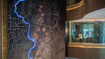 Un intérieur moderne avec une grande carte lumineuse et des formes géométriques, un espace de bureau aux murs de verre et un élément architectural incurvé.