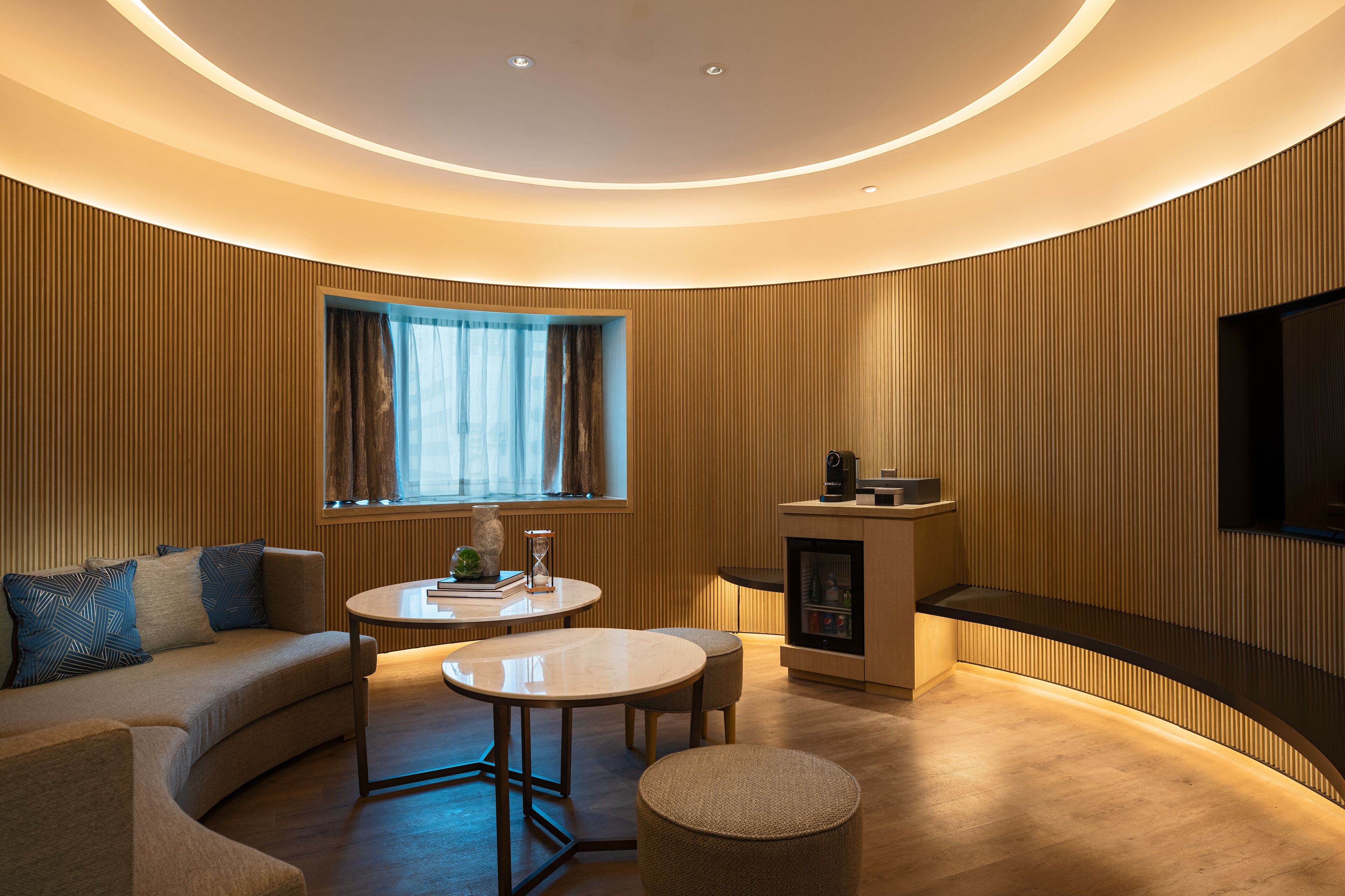 Een moderne woonkamer met een gebogen plafond, een bank, een salontafel en een open haard.