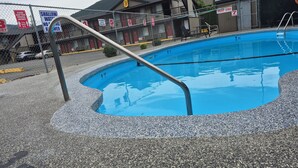 A swimming pool with a metal ladder, surrounded by a fence with numbered signs. - Super 8 by Wyndham Kamloops East (Kamloops)
