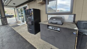 An outdoor seating area with a grill station and a beverage dispenser. - Super 8 by Wyndham Kamloops East (Kamloops)