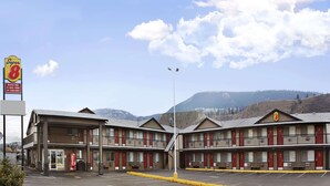 A motel with multiple rooms, a visible Coca-Cola sign, and a mountainous backdrop. - Super 8 by Wyndham Kamloops East (Kamloops)