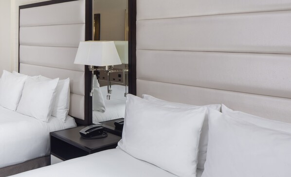 Une chambre d’hôtel avec un lit, une table de chevet, une lampe et un miroir.