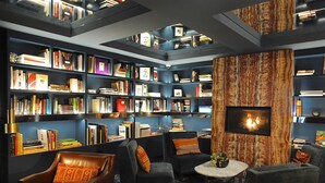 A library with bookshelves, seating, and a fireplace. - Park South Hotel, part of JdV by Hyatt (New York)