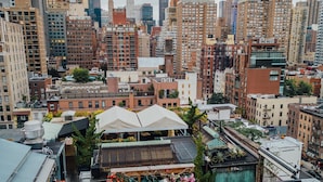 A rooftop restaurant with outdoor seating, surrounded by urban buildings and a clear sky. - Park South Hotel, part of JdV by Hyatt (New York)