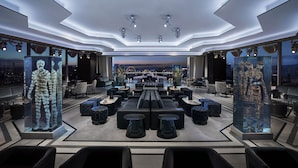 A spacious lobby with a modern design, featuring a central seating area, large windows, and two prominent glass sculptures.