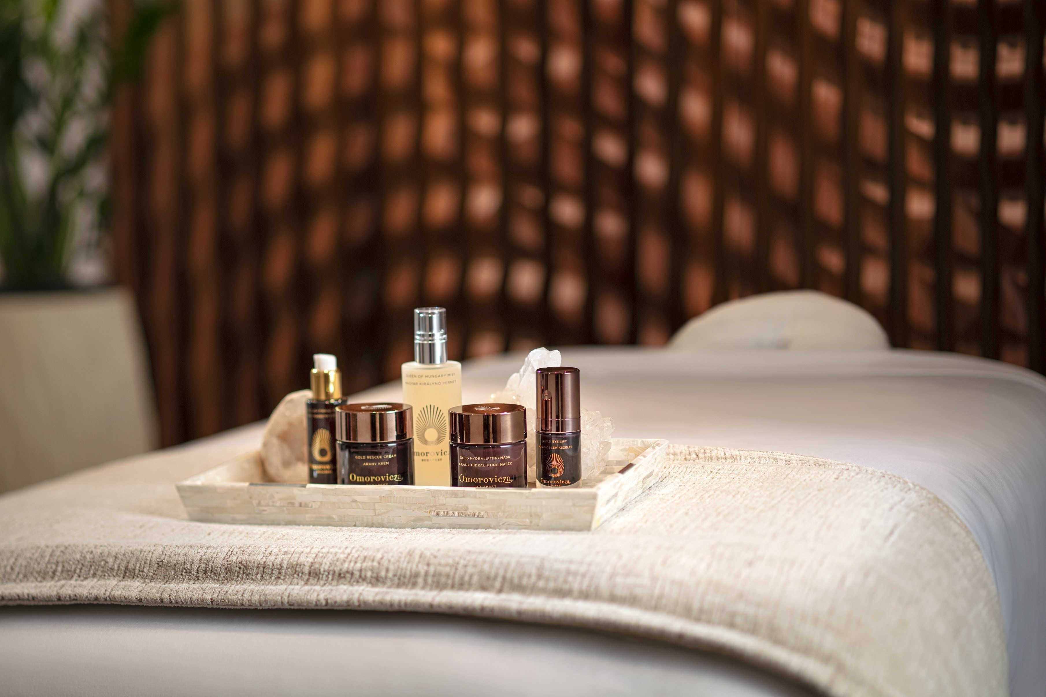 A bed with a tray of skincare products on it.