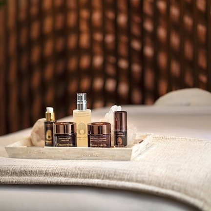 A bed with a tray of skincare products on it.
