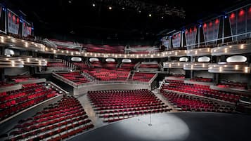 Un teatro amplio y moderno con varios niveles de butacas y un escenario central.