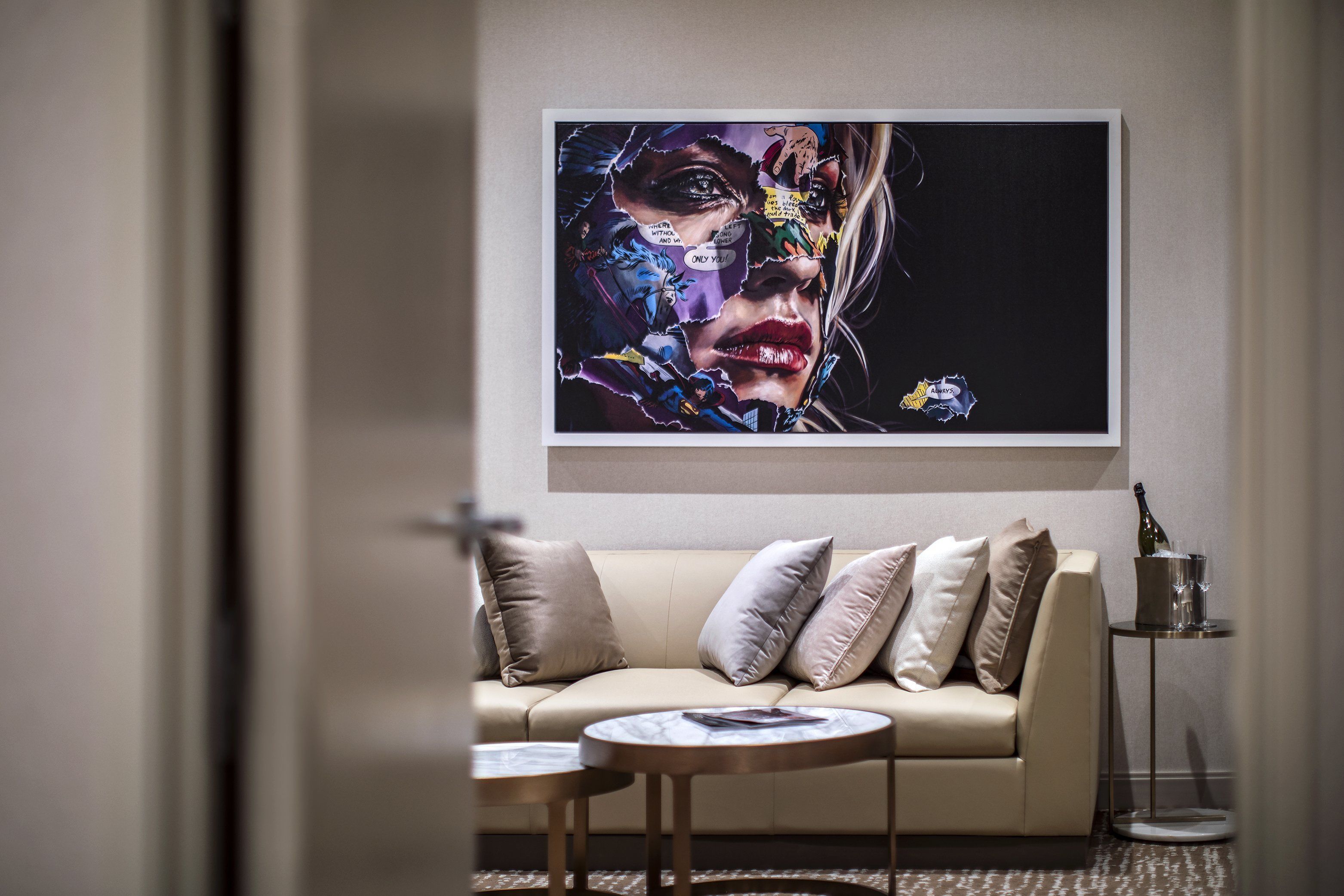 A modern living room with a beige sofa, a marble coffee table, and a framed artwork on the wall.