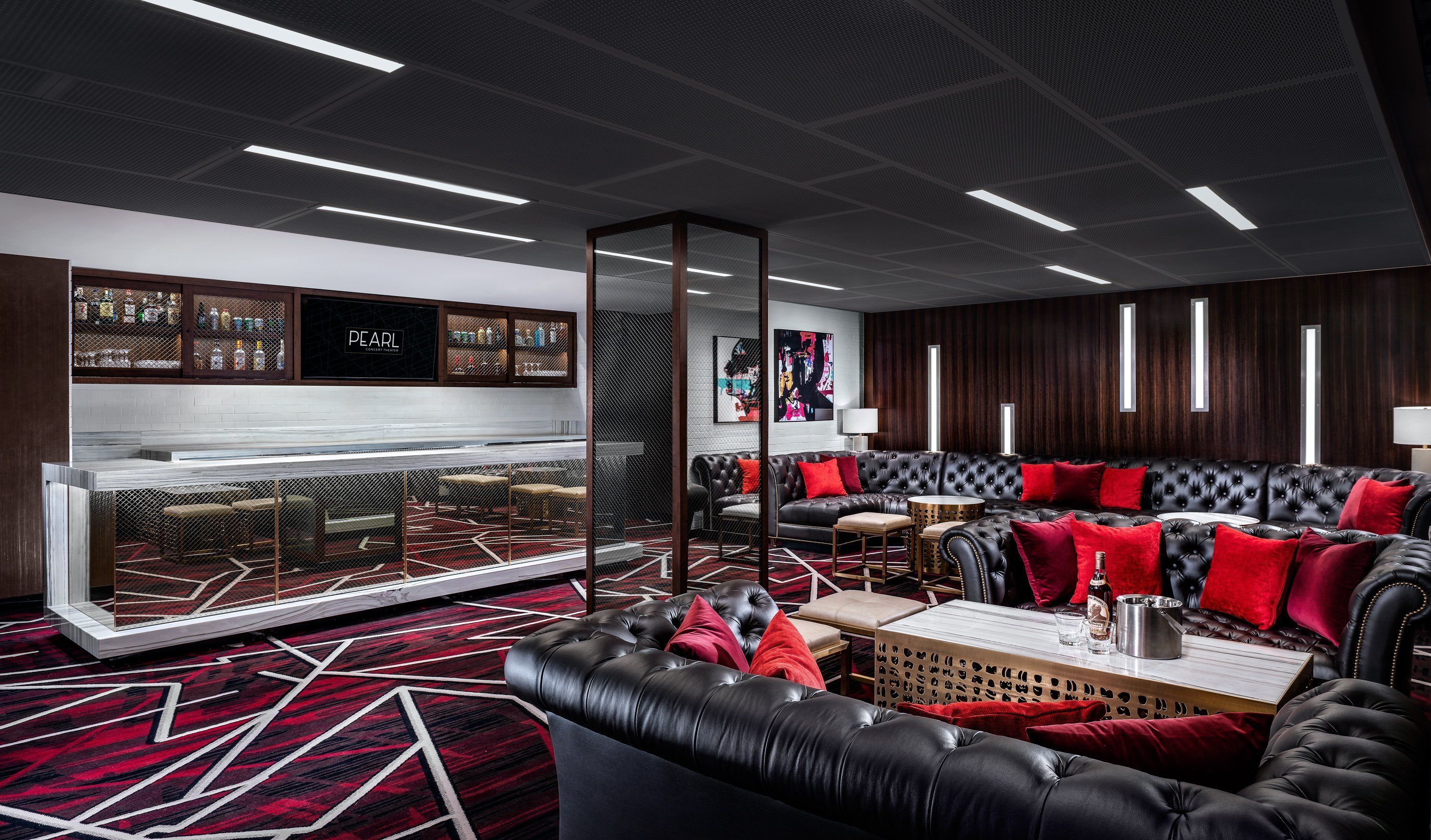 A modern lounge area with a bar, leather sofas, and a patterned carpet.