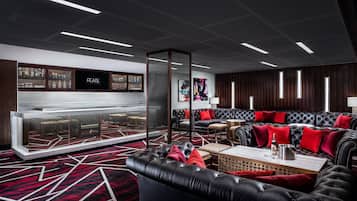A modern lounge area with a bar, leather sofas, and a patterned carpet.