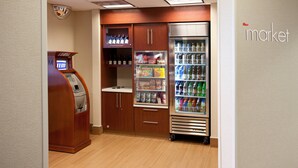 A self-service kiosk, refrigerated food display, and a beverage cooler in a hotel lobby. - SpringHill Suites Los Angeles LAX/Manhattan Beach (Hawthorne)