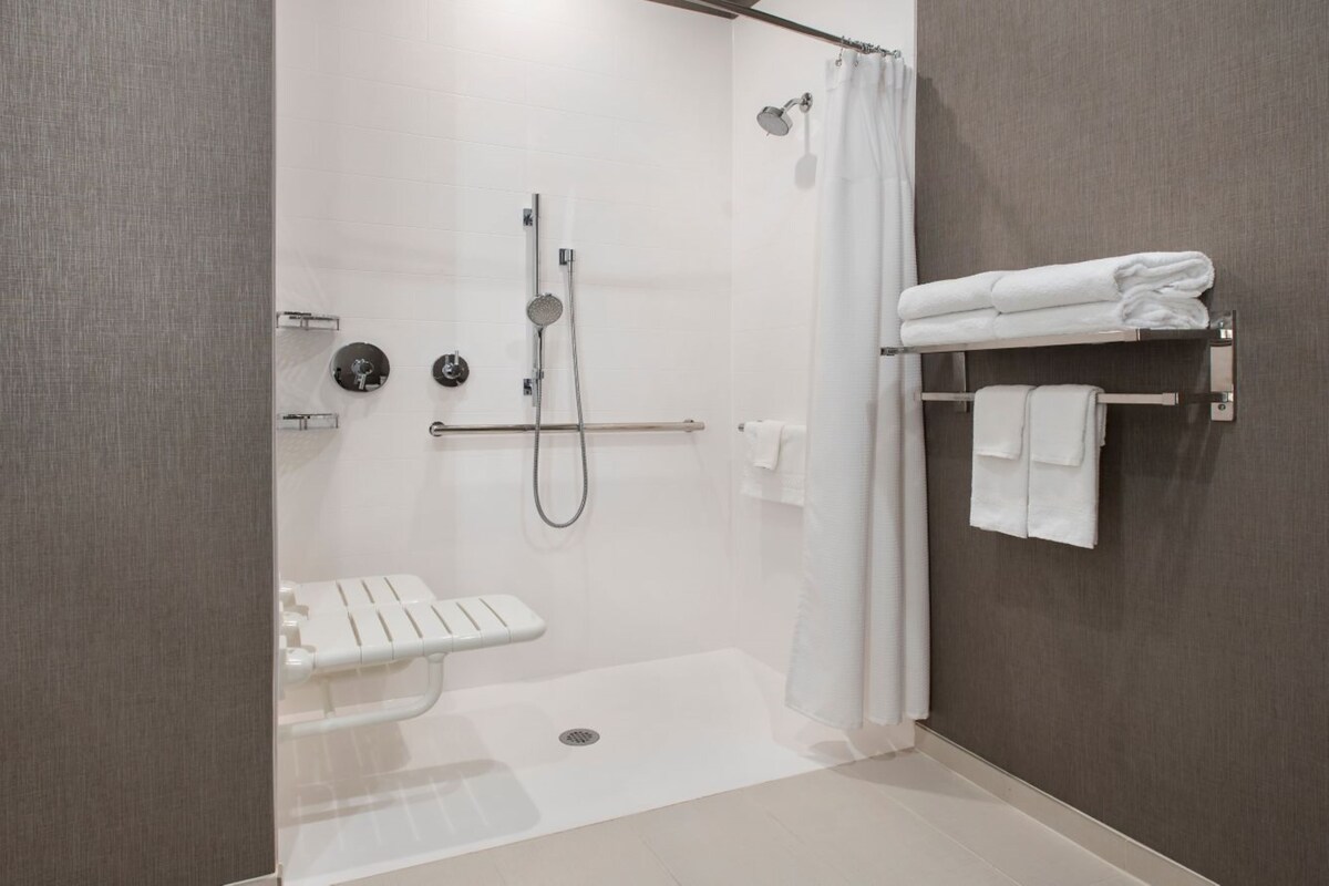 A modern bathroom with a walk-in shower, a toilet, and a towel rack.