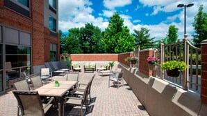 An outdoor patio with a brick floor, outdoor furniture, and potted plants. - Willow Grove Inn (Willow Grove)
