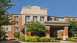 A multi-story hotel with a covered entrance, brick facade, and landscaped garden area. - Willow Grove Inn (Willow Grove)