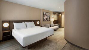 A modern hotel room with a large bed, a sofa, a desk, and a wall-mounted lamp. - AC Hotel by Marriott Old Montreal (Montreal)