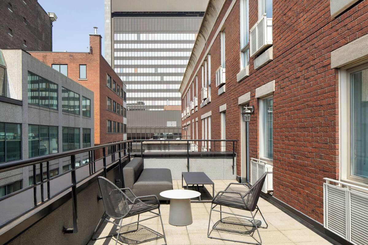 An outdoor patio with a seating area, including a sofa and two chairs, and a table.