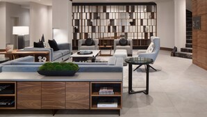 A modern living room with a sectional sofa, armchairs, a coffee table, and a bookshelf. - AC Hotel by Marriott Old Montreal (Montreal)