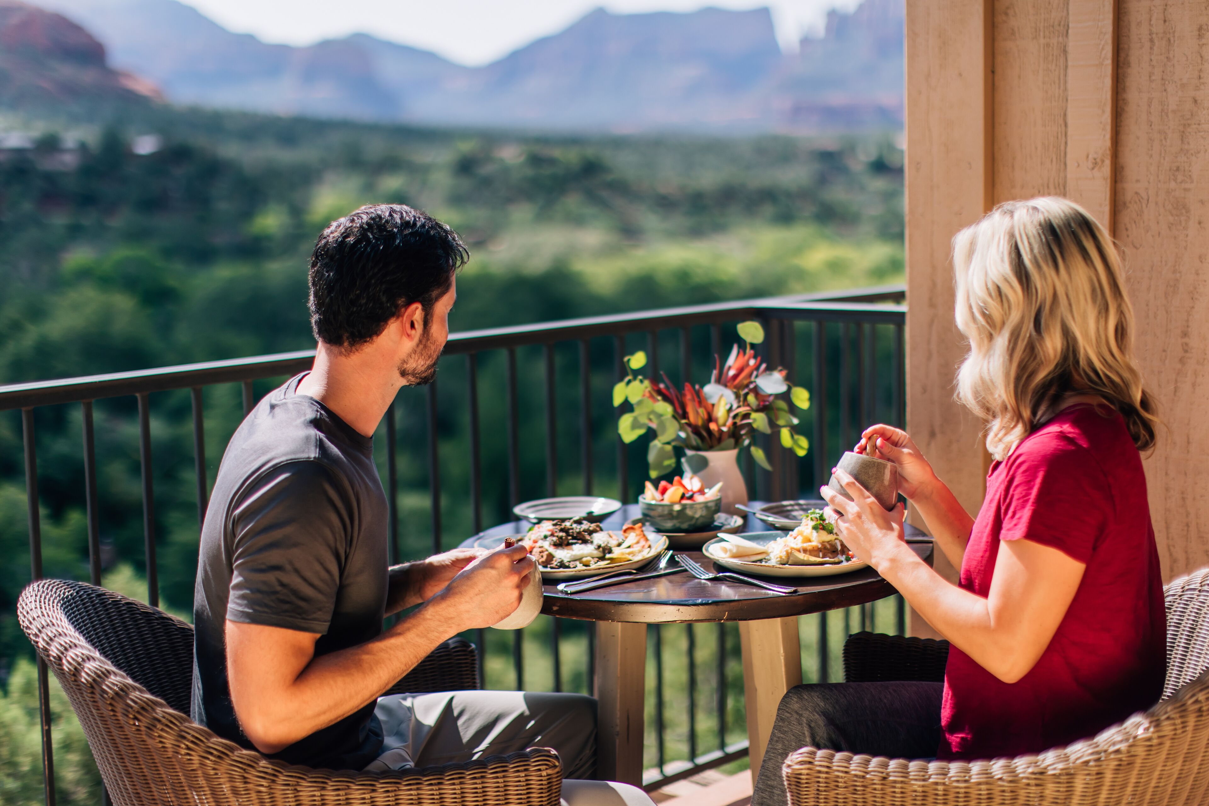 A couple dining at a table with a view of a mountainous landscape.