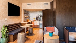A modern living area with a sofa, a coffee table, and a seating area with a bench. There is a kitchen visible in the background with appliances and a countertop. - The Cliffs (Sedona)