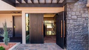 A modern building entrance with a stone wall, a wooden door, and a glass door leading inside. - The Cliffs (Sedona)